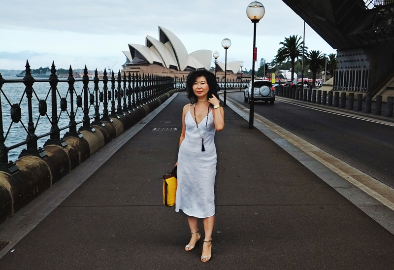 Writer and blogger Vivienne She standing under Sydney Harbour Bridge overlooking Sydney Opera House.