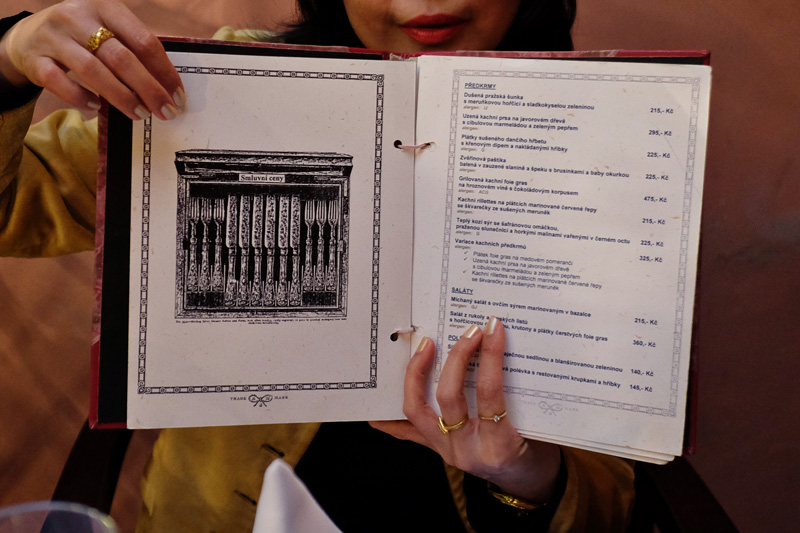The food menu of U Modré kachničky Czech restaurant in Prague. The food menu has a historic illustration of a cutlery canteen of elaborately embellished knives and forks. The Little Blue Duck Czech restaurant review by White Caviar Life.